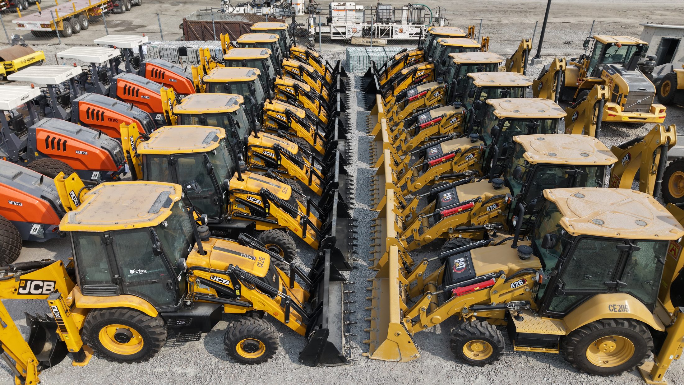 JCB and CAT backhoe loaders parked back to back at the equipment yard