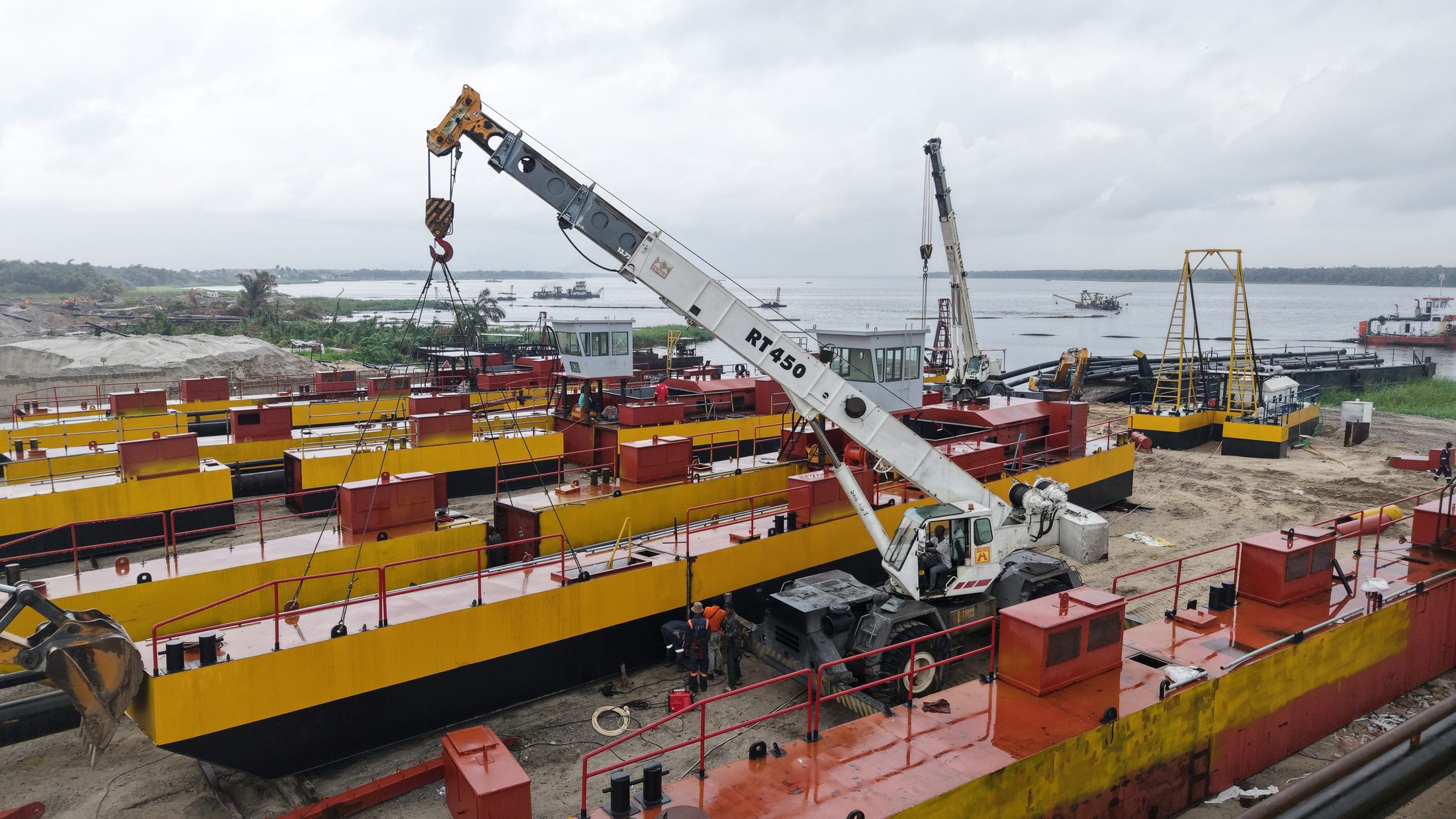 Mobile crane assembling barge sections at the riverside fabrication yard