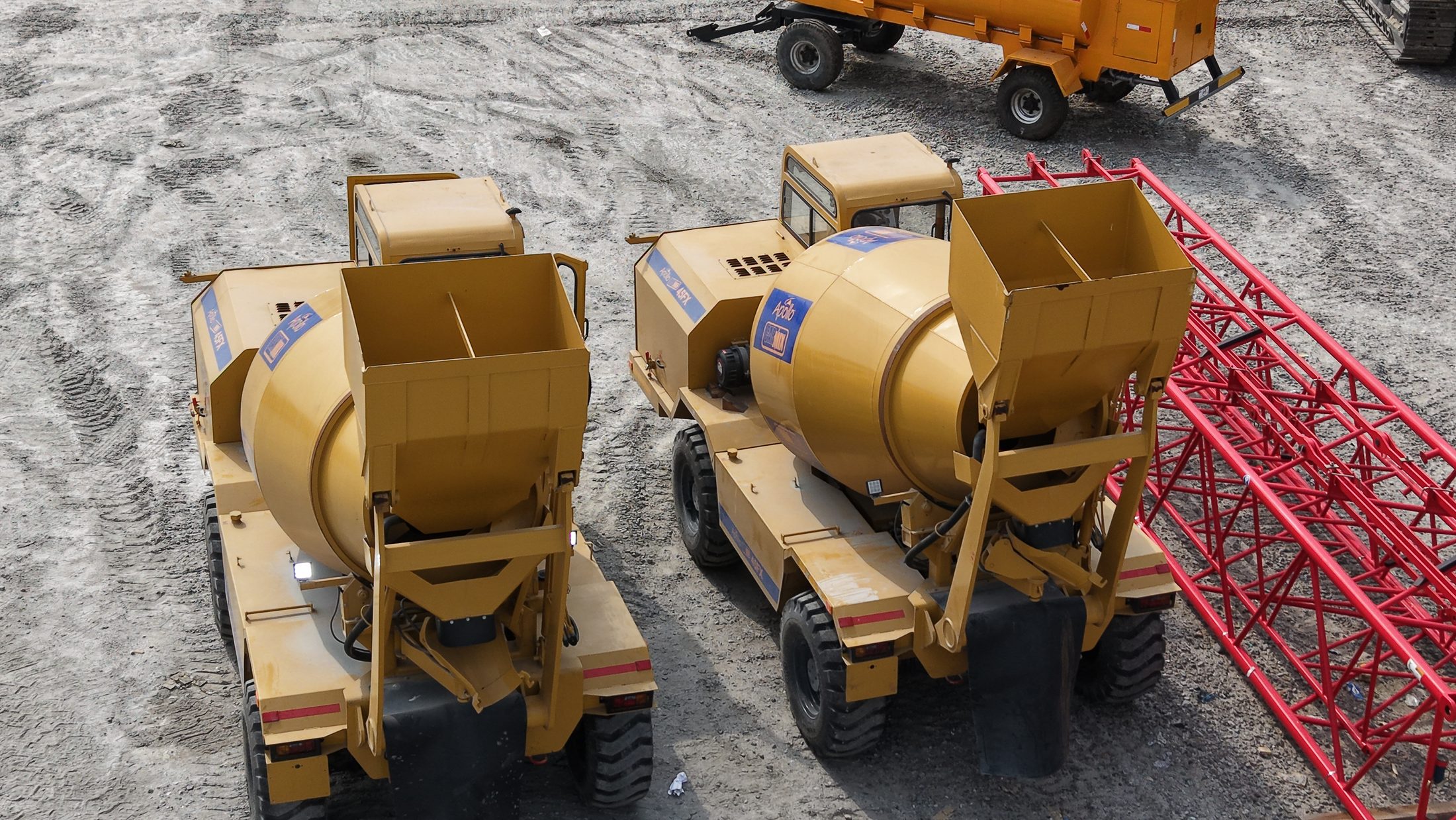 Apollo self-loading concrete mixers parked beside a mobile crane boom