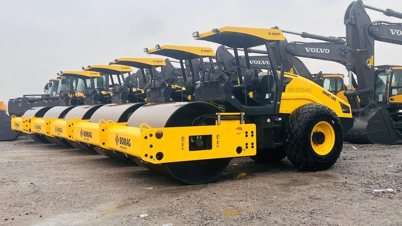 Bomag smooth drum rollers arranged alongside excavators at the plant yard