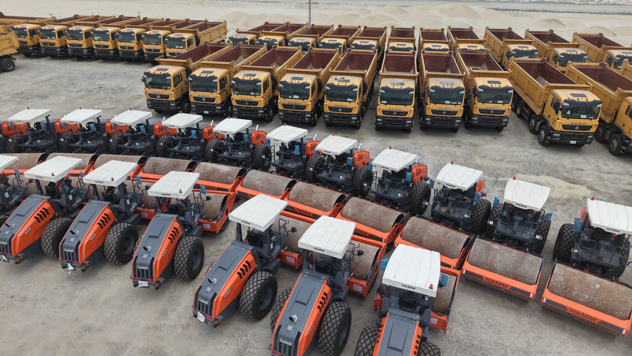 Tipper trucks and Hamm rollers arranged in the equipment yard