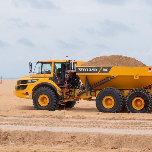 Articulated dump truck moving fill across the beachside workfront in Benin